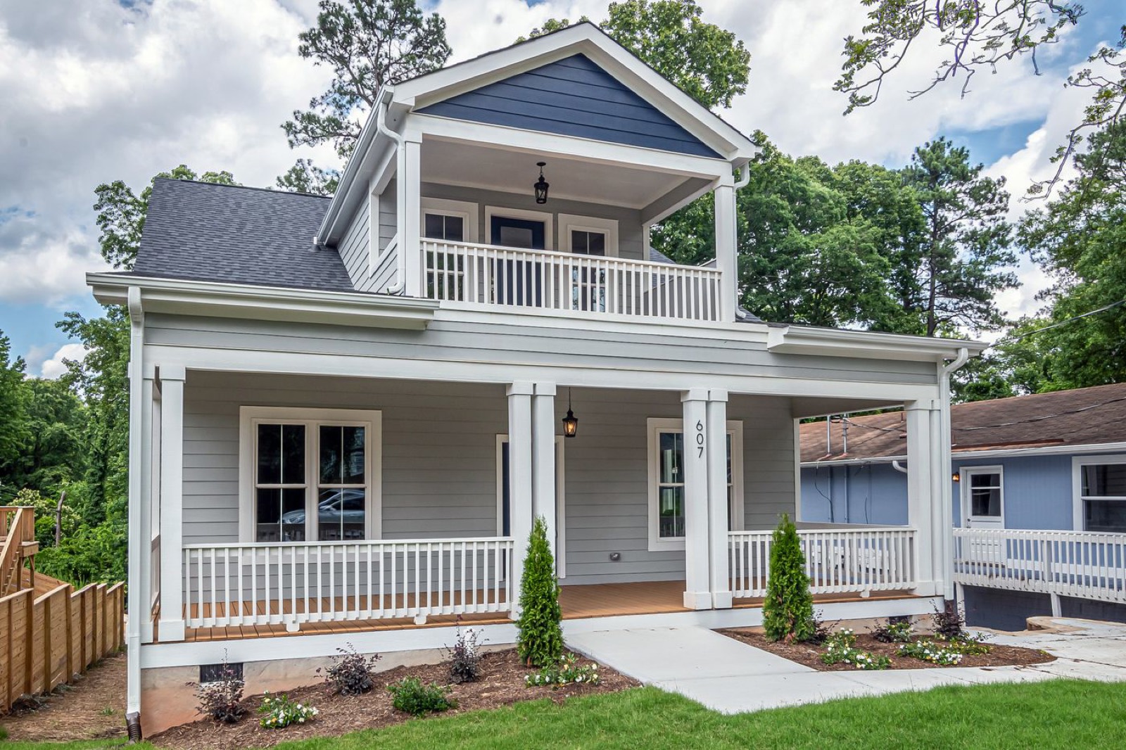 A grey clapboard house with a white front porch.